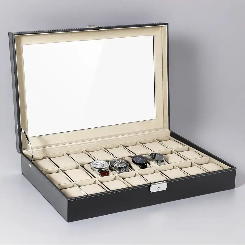 Black 24-slot watch box with glass top open on a grey studio background, cream cushions inside