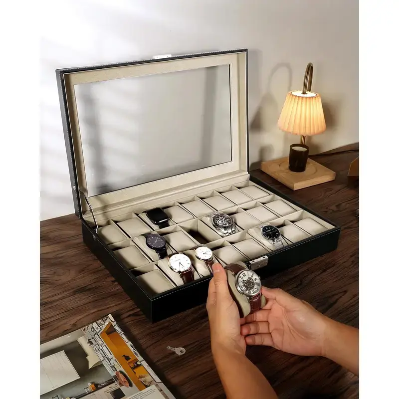 Hands placing a watch onto a cushion of the 24-slot black leather watch box on a desk