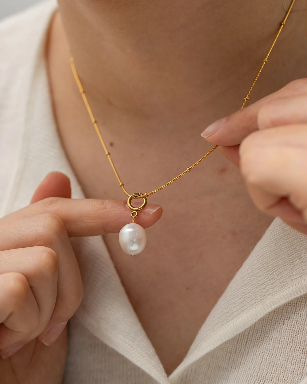 Close-up of freshwater pearl drop pendant on gold-plated bead station chain