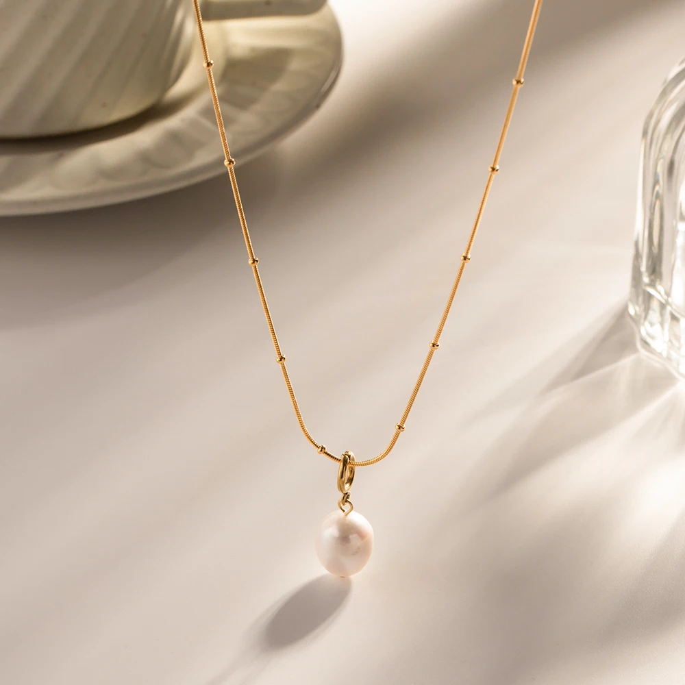 Freshwater pearl pendant necklace styled flat lay in warm light