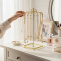 Crown Carousel Jewelry Stand — gold-tone iron necklace stand with glass tray base on a vanity